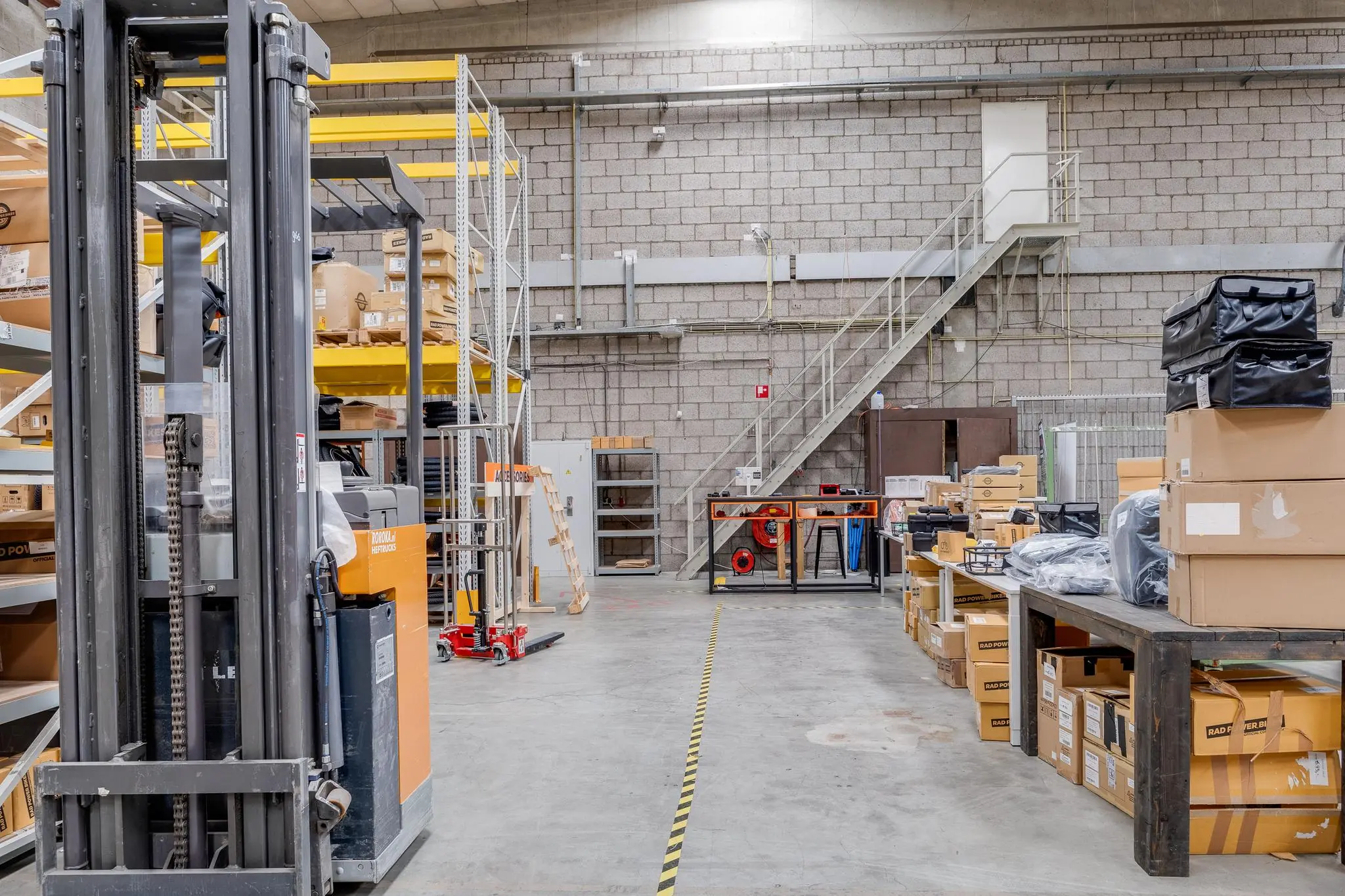 Magazijnruimte aan de Zonnebaan met stellingen, een heftruck en stapels dozen.