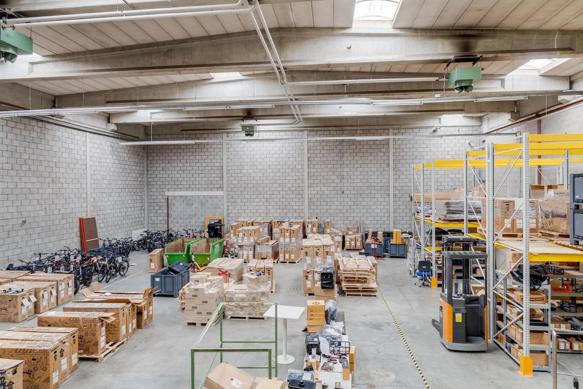 Ruime opslagloods aan de Zonnebaan met stapels dozen, fietsen en magazijnstellingen.