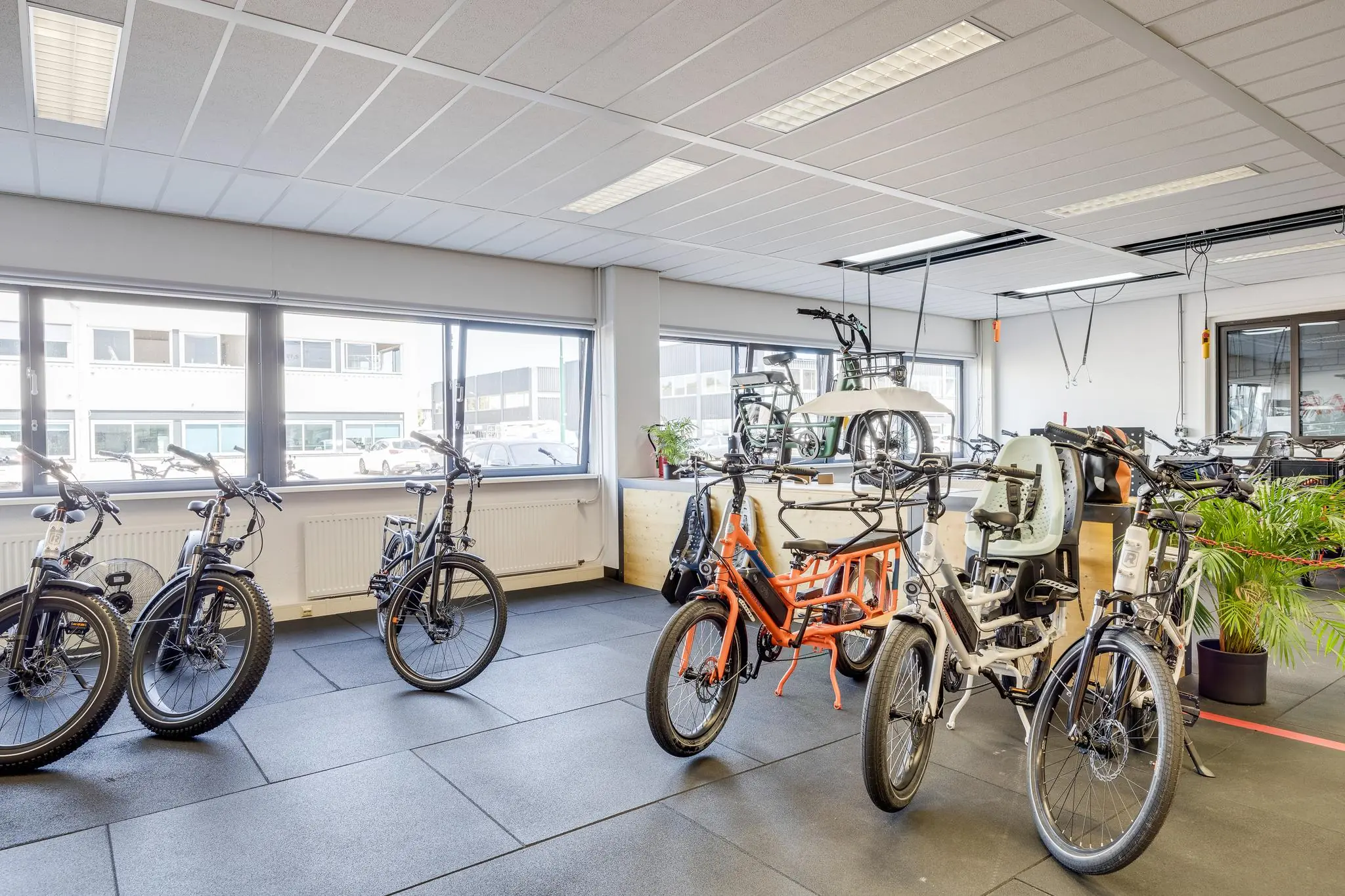 Showroom met verschillende elektrische fietsen bij Zonnebaan, met daglichtinval door grote ramen.