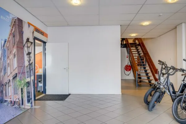 Entree van een servicepunt met trap naar boven en elektrische fietsen op de voorgrond.