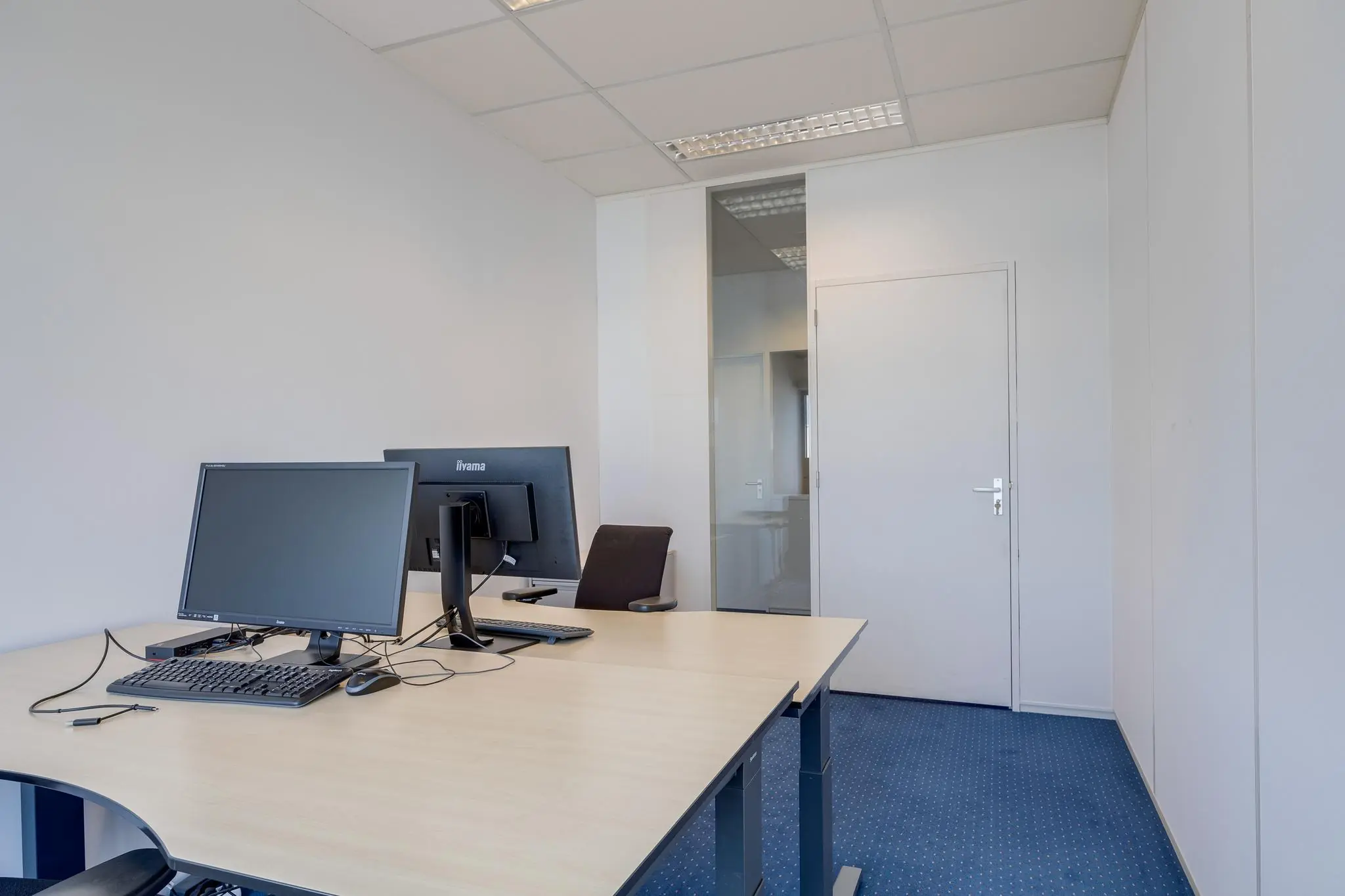 Kleine, moderne kantoorruimte aan de Zonnebaan met twee bureaus en computerschermen.