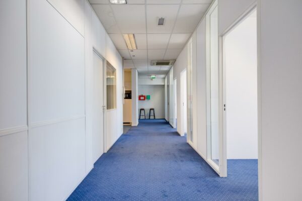 Lichte kantoorruimte aan de Zonnebaan met blauwe vloerbedekking en glazen kantoordeuren.