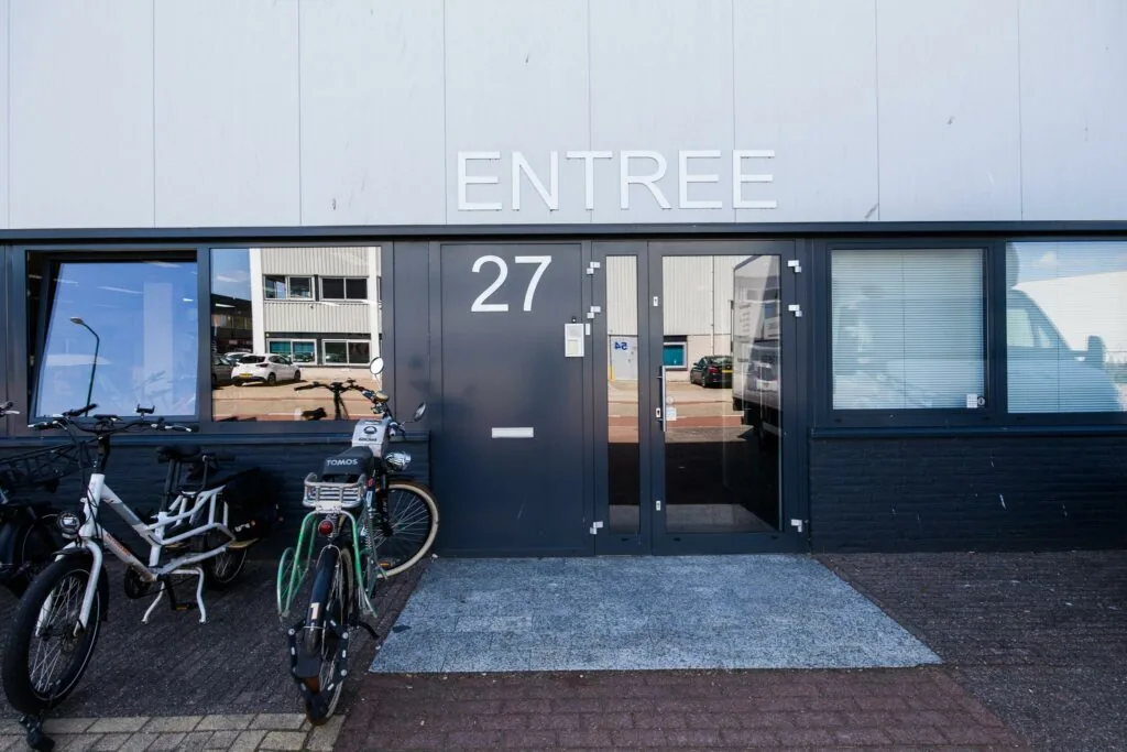 Voordeur met nummer 27 en opschrift "ENTREE" aan de Zonnebaan, met fietsen geparkeerd ervoor.