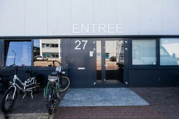 Voordeur met nummer 27 en opschrift "ENTREE" aan de Zonnebaan, met fietsen geparkeerd ervoor.