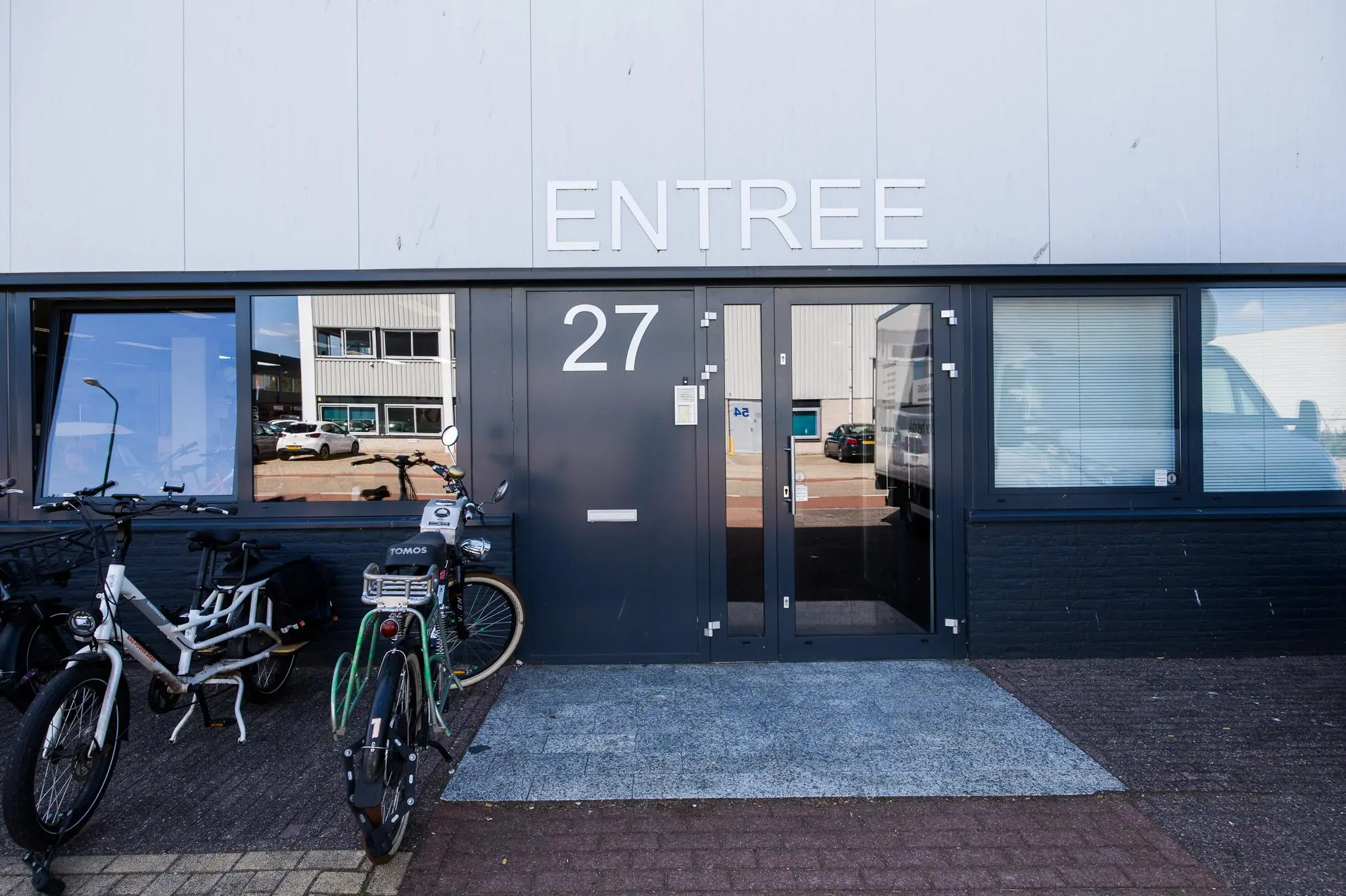 Voordeur met nummer 27 en opschrift "ENTREE" aan de Zonnebaan, met fietsen geparkeerd ervoor.