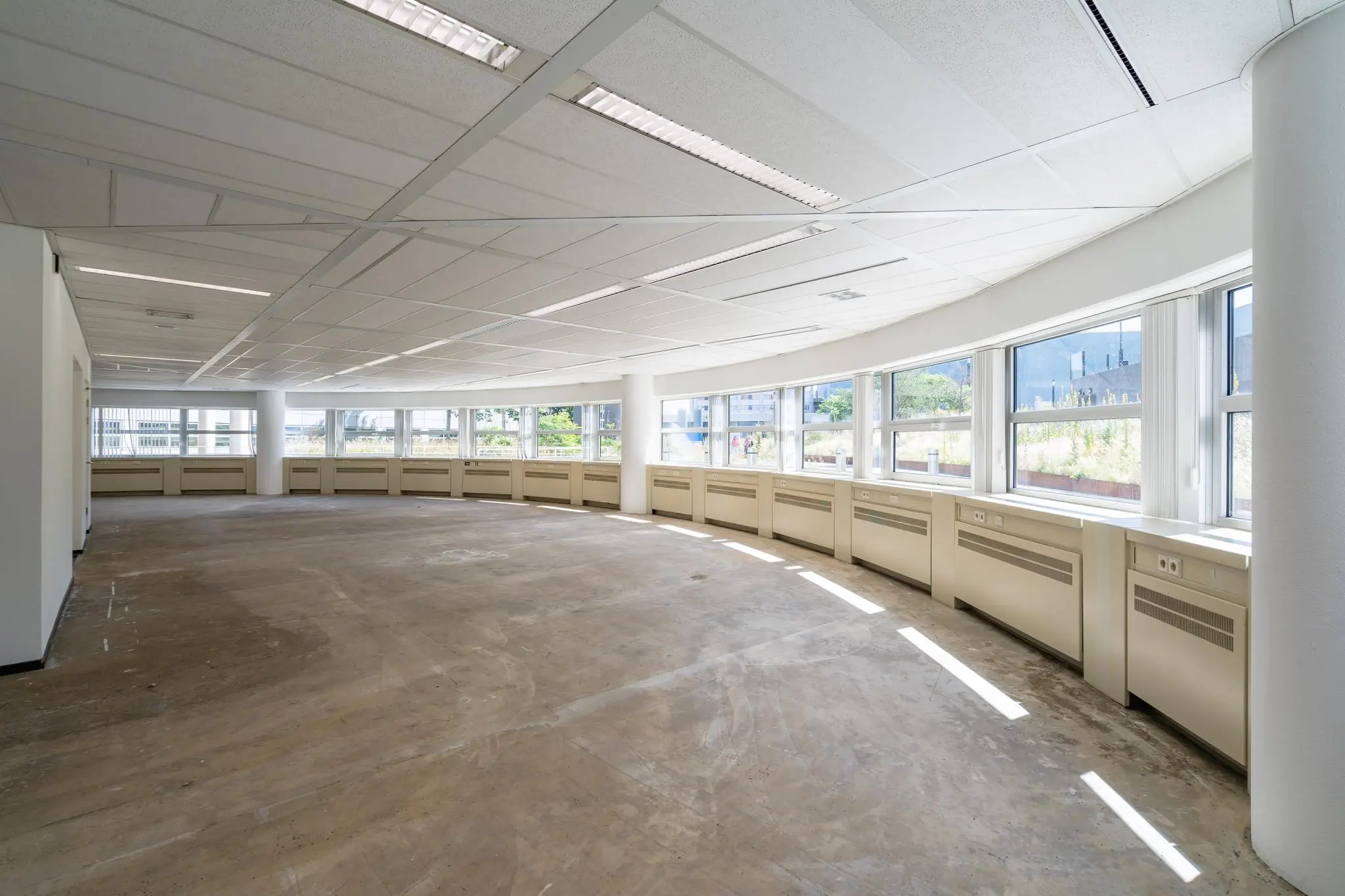 Licht en ruim leegstaand kantoorpand aan het Churchillplein met grote ramen en systeemplafond.