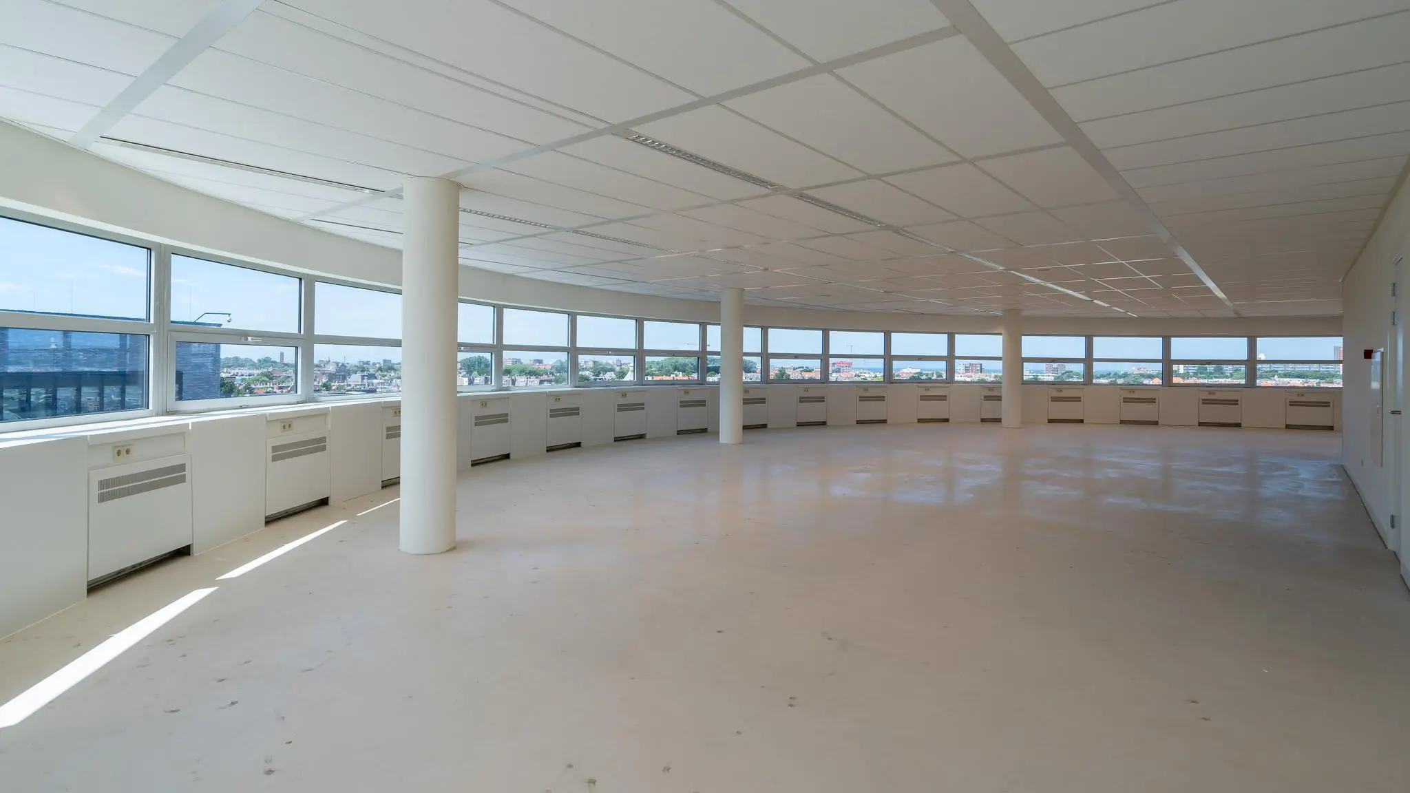 Lichte, lege kantoorruimte met panoramisch uitzicht op de stad vanaf het Churchillplein.