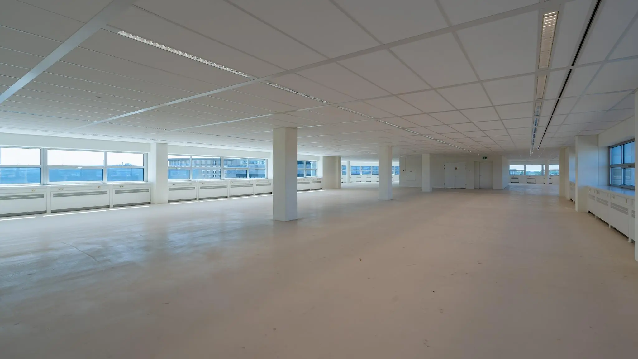 Leeg en licht kantoorpand aan het Churchillplein met grote ramen en systeemplafond.