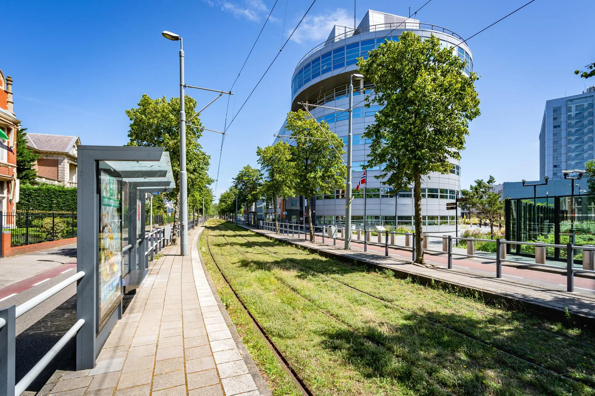Trambaan en halte aan het Churchillplein in Den Haag met moderne kantoorgebouwen en groene bomen.