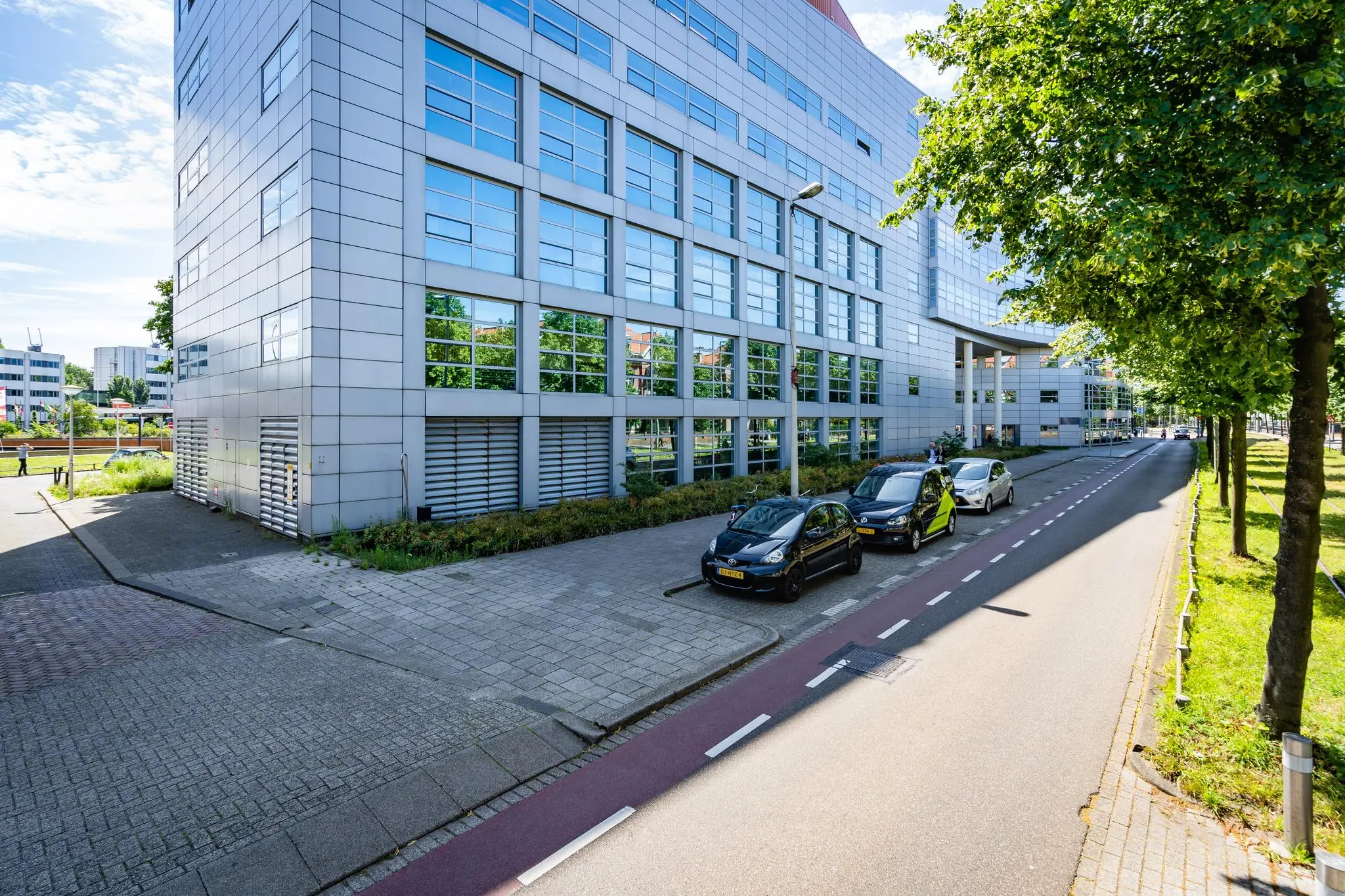 Straatbeeld van het Churchillplein met geparkeerde auto's naast een modern kantoorgebouw in Den Haag.