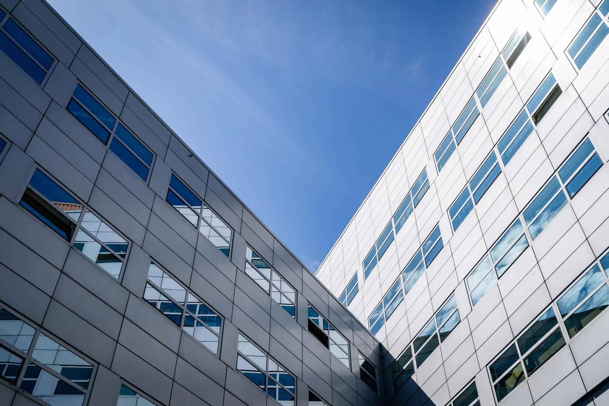 Moderne witte kantoorgebouwen op het Churchillplein met spiegelende ramen onder een blauwe lucht.