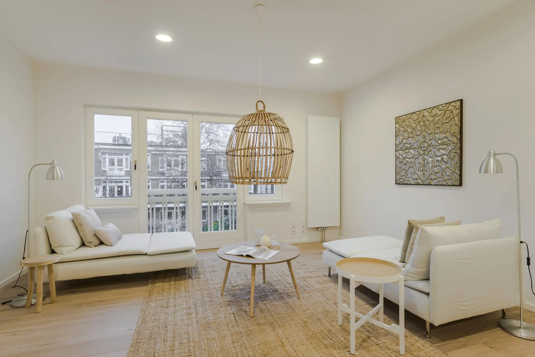 Licht en modern ingericht zitgedeelte in een appartement aan het Concertgebouwplein met neutrale tinten en natuurlijke materialen.