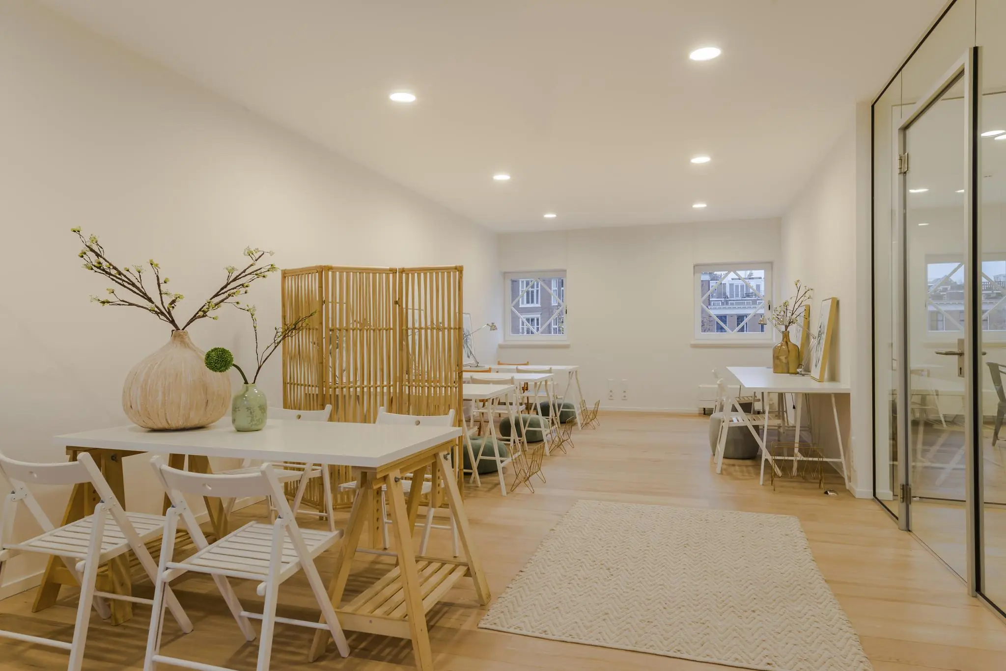 Licht ingerichte werkruimte op Concertgebouwplein met houten accenten, witte meubels en decoratieve vazen.