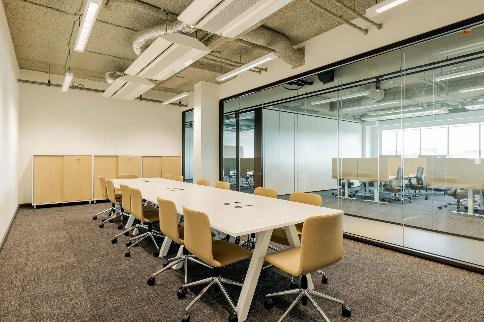 Moderne vergaderruimte met lange witte tafel, beige stoelen en glazen wand in kantoorgebouw aan het Weena.