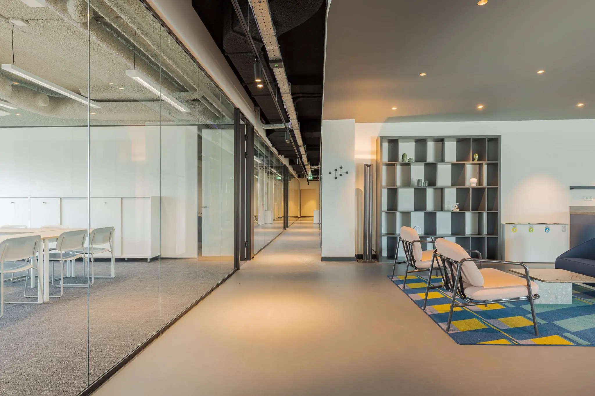 Modern kantoorinterieur aan de Weena met glazen vergaderruimtes, loungehoek en open gangpad.