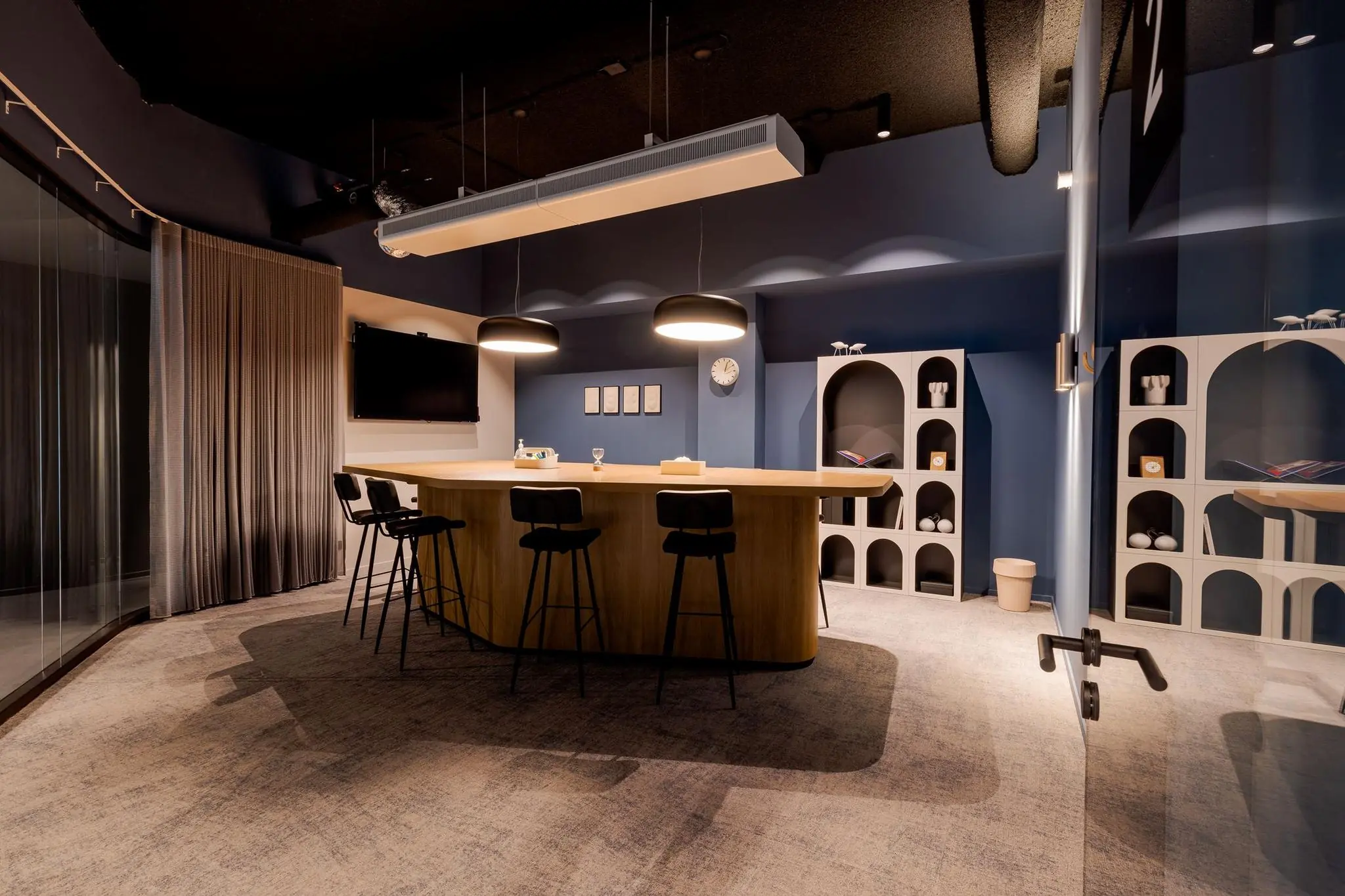 Moderne vergaderruimte aan het Weena met een houten ovale tafel, zwarte barkrukken, sfeerverlichting en stijlvolle wandrekken.