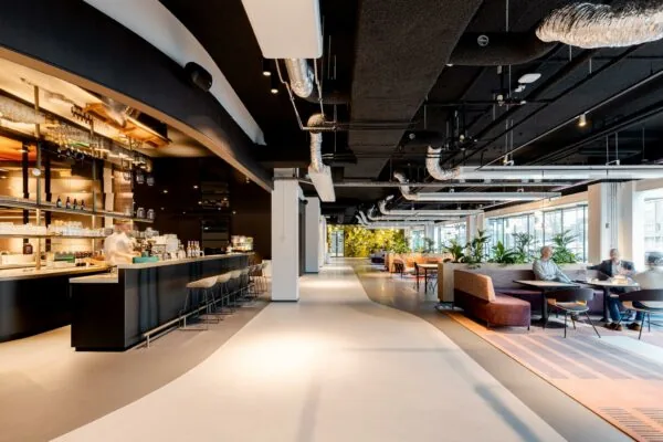 Moderne, open kantoorlobby aan het Weena met een stijlvolle bar en zitgedeelte omringd door veel daglicht en groen.