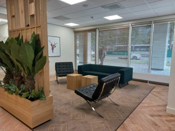 Moderne wachtruimte met designmeubels, houten accenten, kamerplanten en grote ramen met jaloezieën aan de Weena.