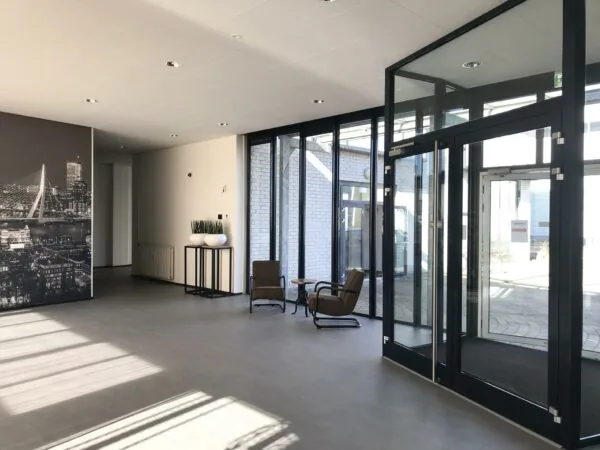 Moderne, lichte entreehal aan de Cypresbaan met glazen deuren, zitgelegenheid en een grote wandfoto van Rotterdam.