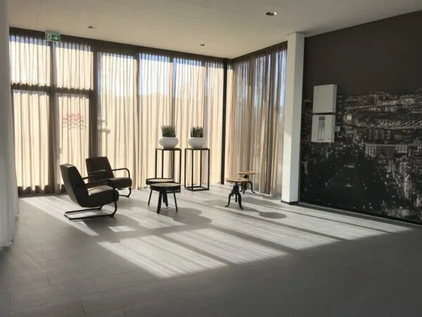 Lichte wachtruimte aan de Cypresbaan met moderne stoelen, planten en een grote stadsfoto op de muur.