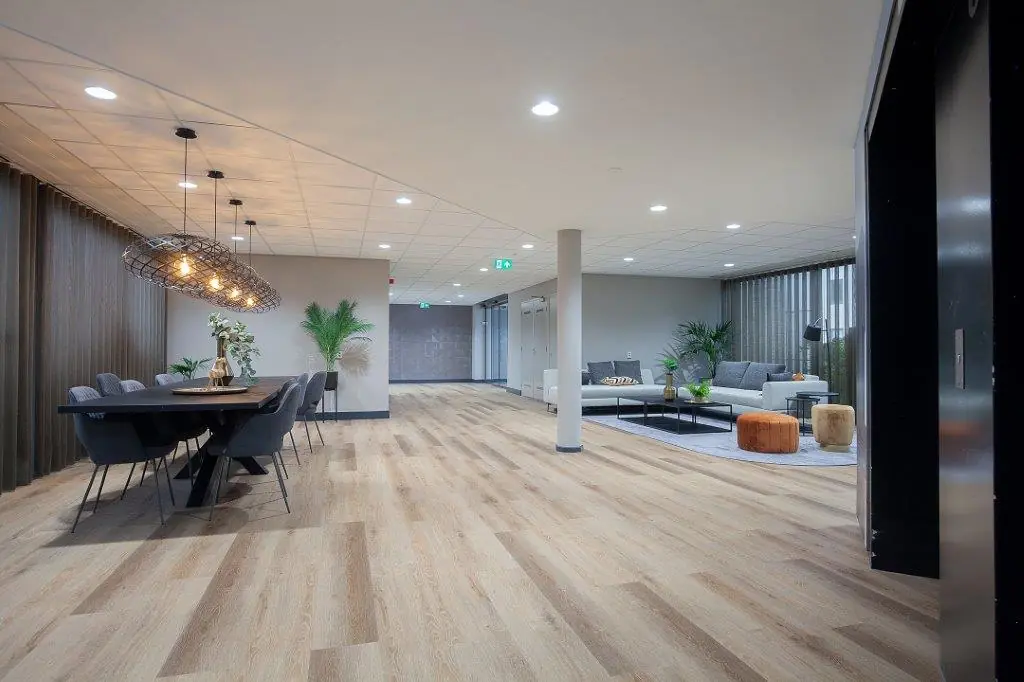 Moderne, sfeervol ingerichte gemeenschappelijke ruimte aan de Cypresbaan met zithoek, eettafel en houten vloer.