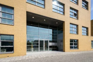 Voorgevel van het kantoorgebouw Tri Colore II in Capelle aan den IJssel met gele bakstenen en grote glazen entree.