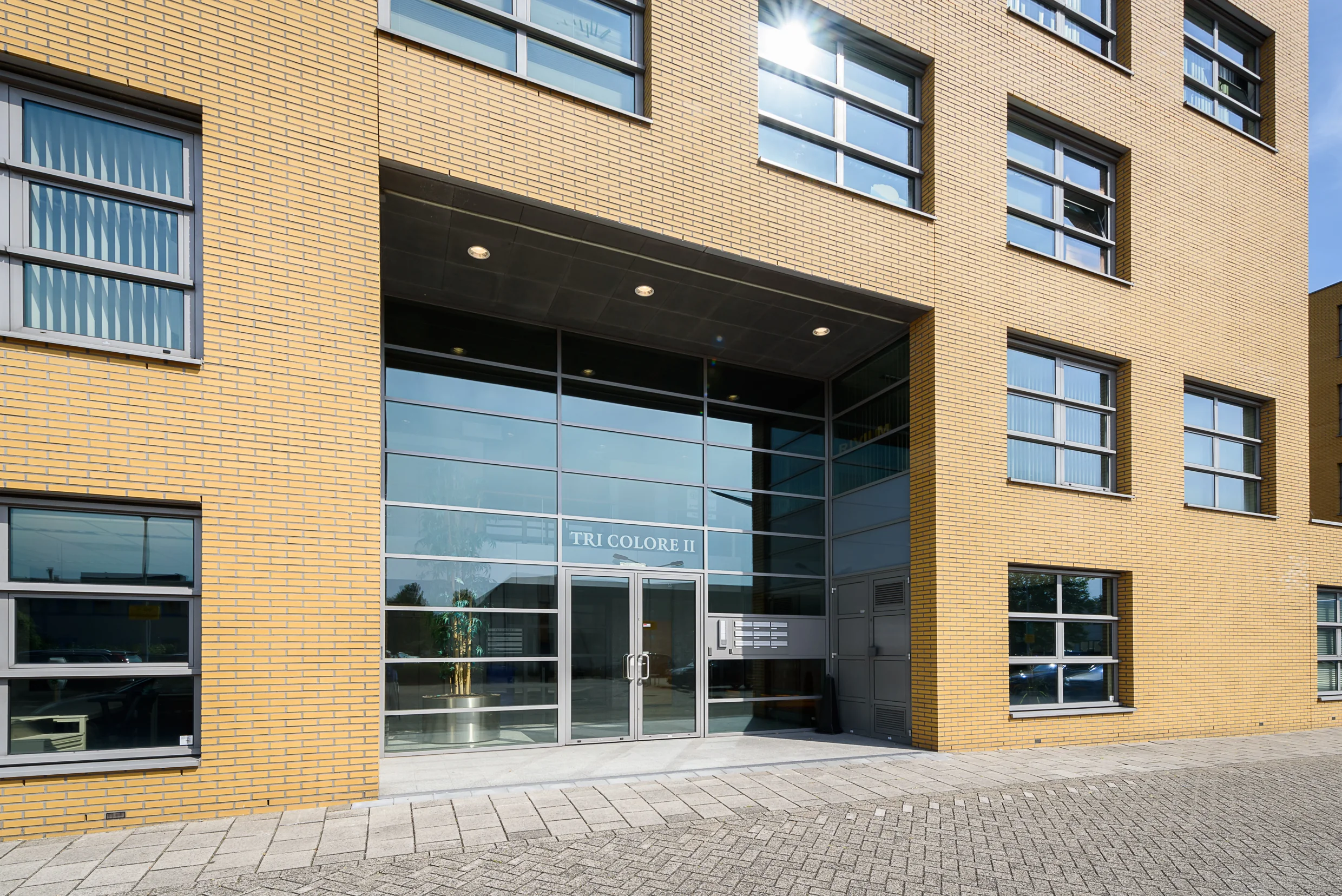 Voorgevel van het kantoorgebouw Tri Colore II in Capelle aan den IJssel met gele bakstenen en grote glazen entree.