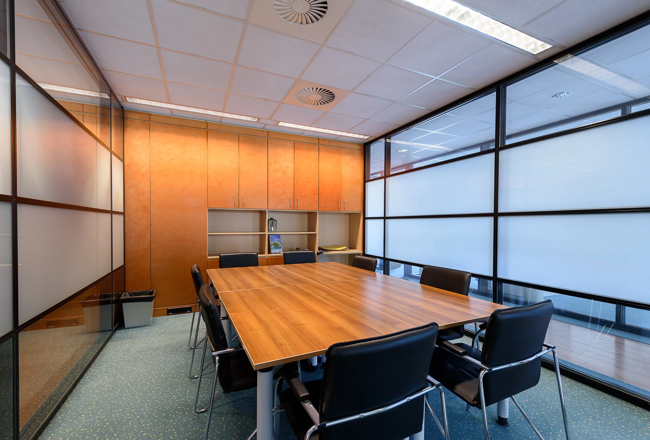 Vergaderruimte in Capelle aan den IJssel met houten tafel, zwarte stoelen en kastenwand.