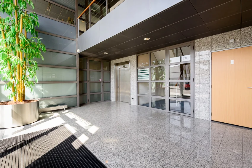 Moderne en lichte entreehal van het kantoorgebouw Tricolore in Capelle aan den IJssel met lift en grote binnenplant.