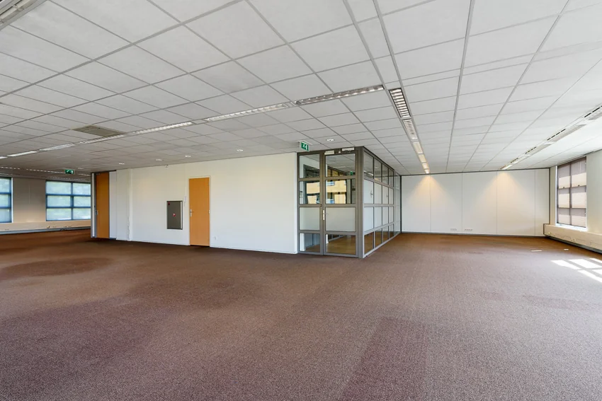 Ruime, lege kantoorruimte op de tweede etage van het Tricolore-gebouw in Capelle aan den IJssel met systeemplafond, grote ramen en glazen vergaderruimte.