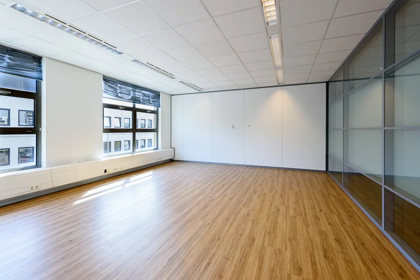 Lichte, lege kantoorruimte op de tweede etage van Tricolore in Capelle aan den IJssel met houten vloer en glazen wand.