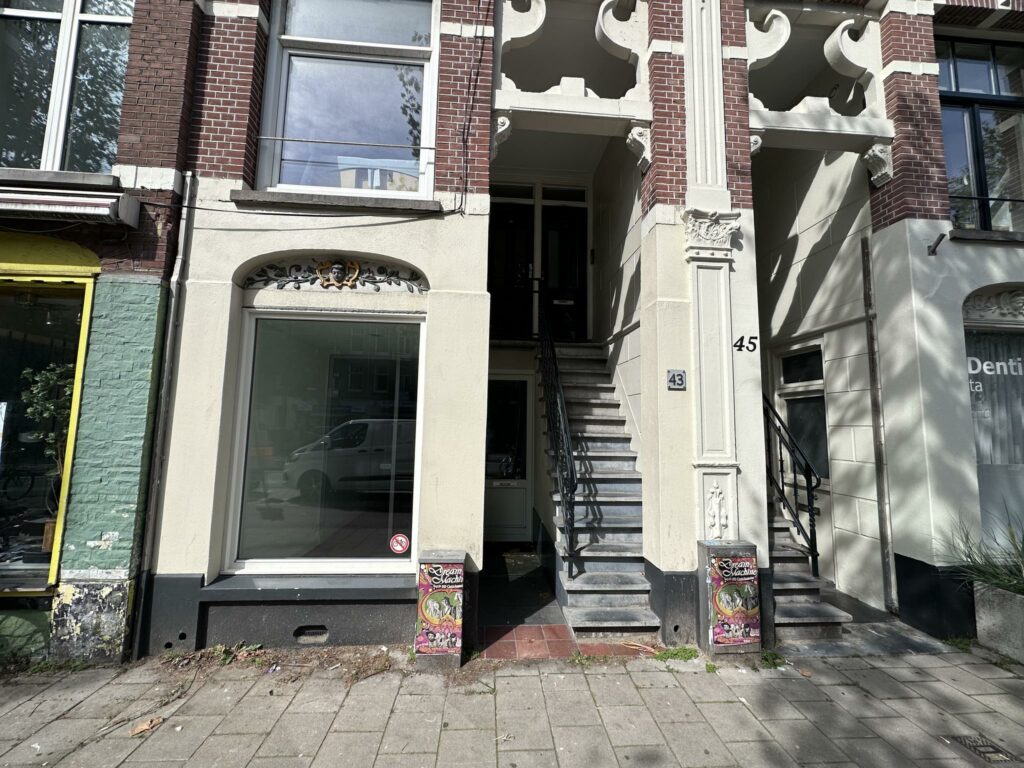 Voorgevel van een pand aan de Ceintuurbaan met huisnummers 43 en 45, brede trapopgang en versierde prullenbak op de stoep.