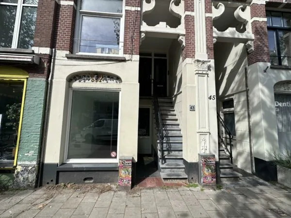 Voorgevel van een pand aan de Ceintuurbaan met huisnummers 43 en 45, brede trapopgang en versierde prullenbak op de stoep.