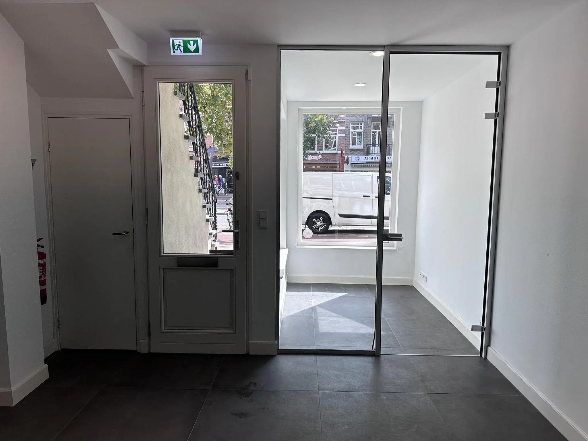 Inkomhal met glazen deur en doorkijk naar de Ceintuurbaan met geparkeerde witte bestelbus.
