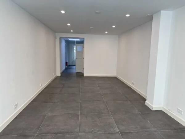 Leeg, smal winkel- of kantoorpand aan de Ceintuurbaan met grijze vloertegels en witte muren.