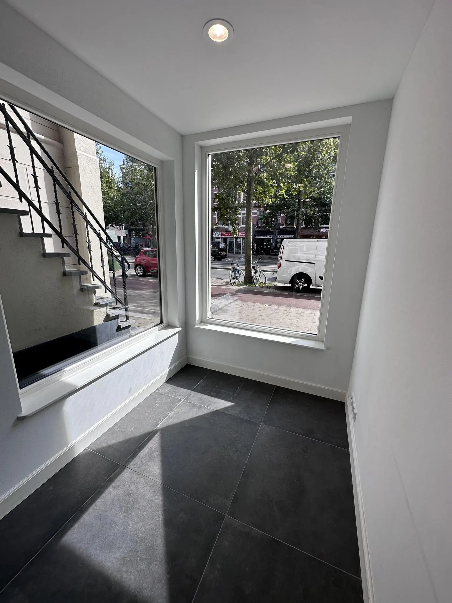 Kleine, lege hoekruimte met grote ramen aan de Ceintuurbaan en zicht op de straat met auto's en fietsen.