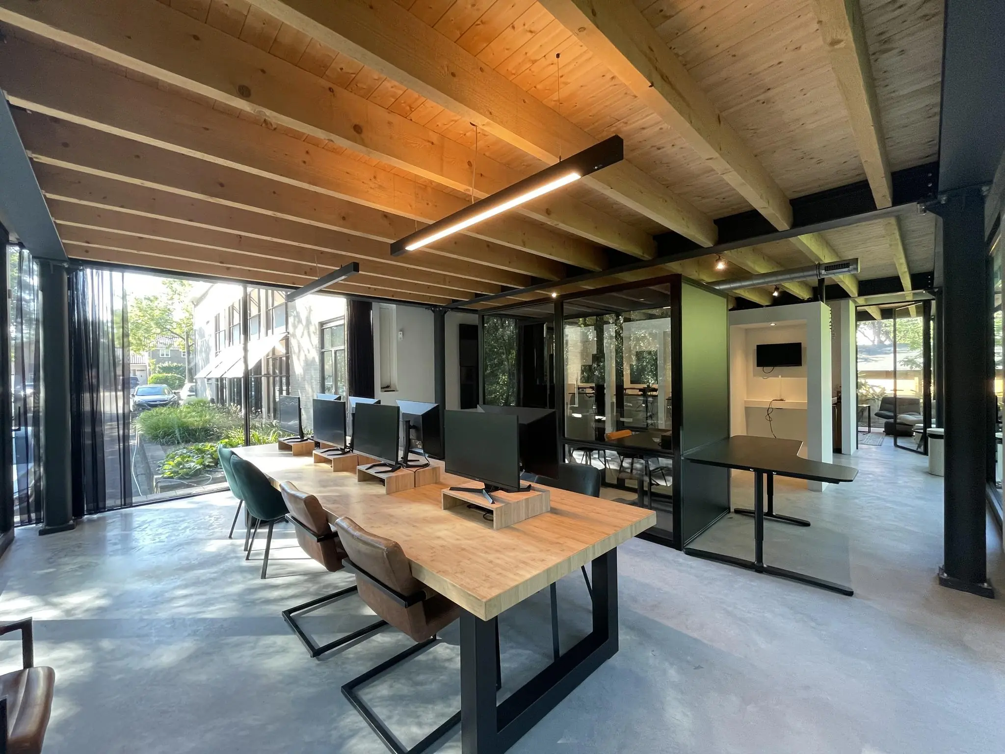 Modern kantoorinterieur aan de Sloterweg met houten plafond en werkplekken bij grote ramen.