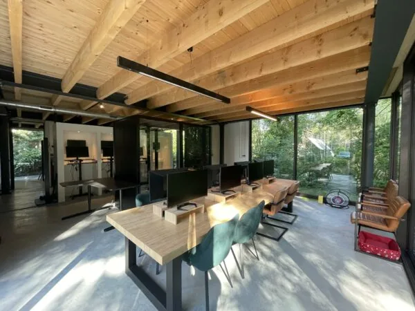 Modern kantoorinterieur aan de Sloterweg met houten plafond, werkplekken en grote ramen met uitzicht op groen.