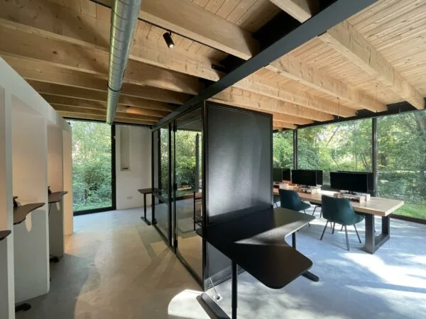 Modern kantoorinterieur aan de Sloterweg met houten plafond, glazen wanden en werkplekken met uitzicht op groen buitengebied.