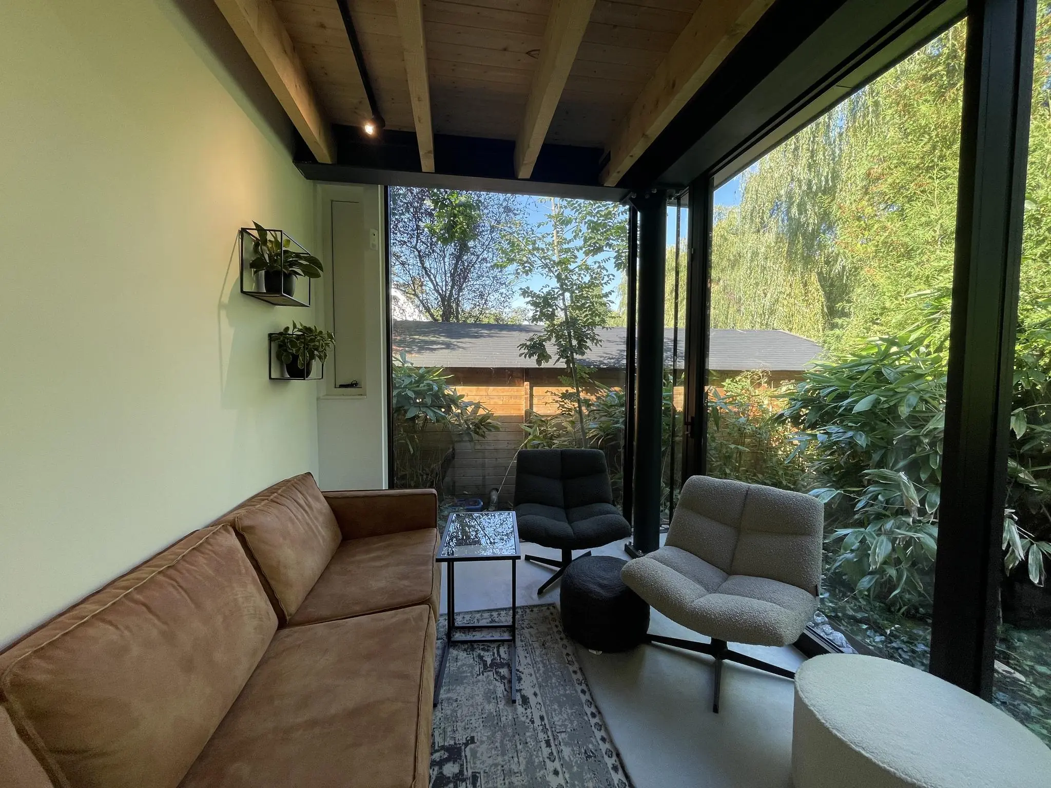 Modern ingerichte zithoek aan de Sloterweg met grote ramen en uitzicht op een groene tuin.