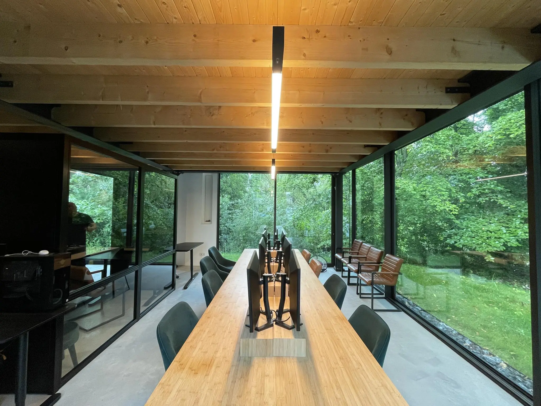 Moderne kantoorruimte aan de Sloterweg met houten plafond, lange werktafel en grote ramen met uitzicht op groen.