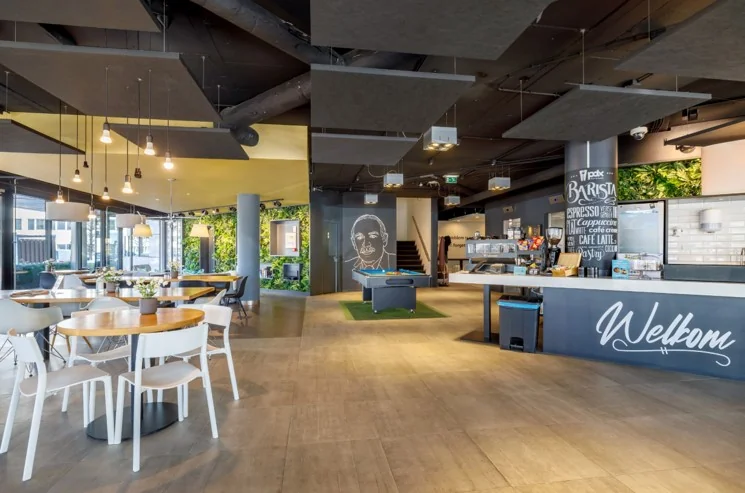 Moderne ontvangst- en ontmoetingsruimte met zitplaatsen, koffiebalie en speeltafel aan de Hogehilweg.