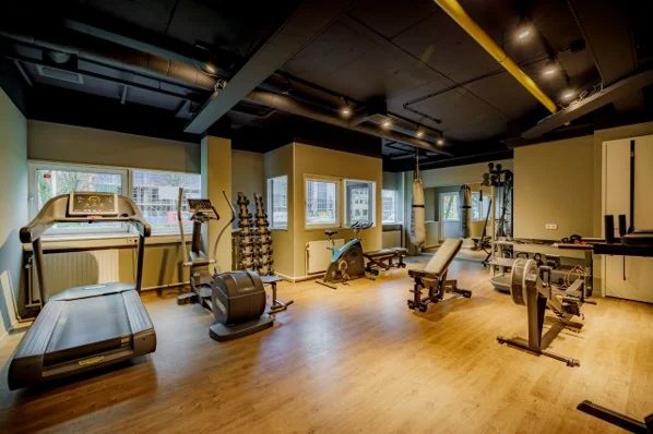 Moderne fitnessruimte aan de Hogehilweg met diverse cardio- en krachttoestellen op een houten vloer.