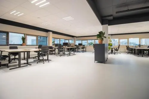 Moderne, ruime kantoorsetting aan de Hogehilweg met bureaus, stoelen en grote ramen met uitzicht op de stad.