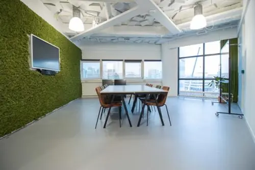 Vergaderruimte aan de Hogehilweg met een moderne inrichting, groene moswand, grote ramen en een lange tafel met stoelen.