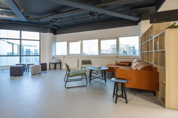 Moderne loungehoek met een bruine bank, stoelen en tafels in een kantoor aan de Hogehilweg.