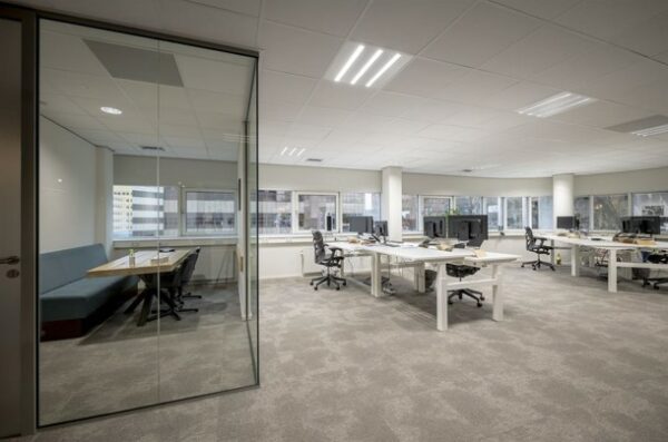 Modern kantoorinterieur aan de Hogehilweg met open werkplekken en een vergaderruimte met glazen wand.
