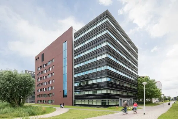 Modern kantoorgebouw aan de Hullenbergweg met roodbruine en zwarte gevels, omgeven door groen en fietspad.