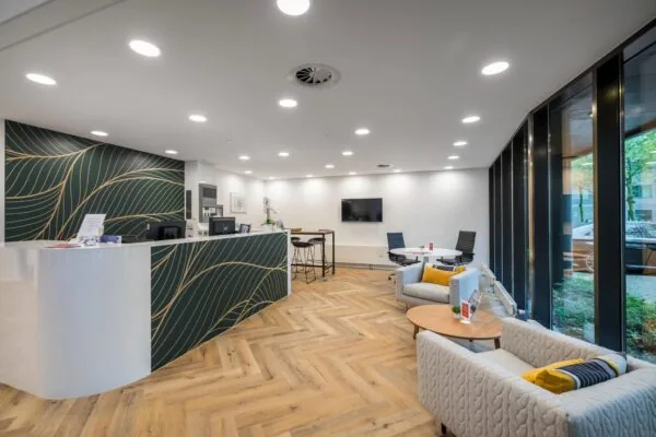 Moderne ontvangsthal aan de Hullenbergweg met een receptiebalie, zithoek en vergadertafel in een stijlvolle, lichte ruimte.