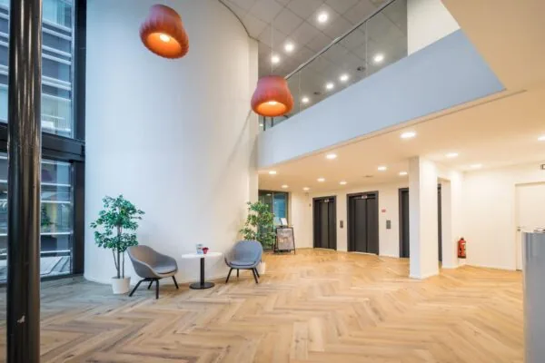 Moderne, lichte ontvangsthal aan de Hullenbergweg met zithoek, houten visgraatvloer en drie liften.